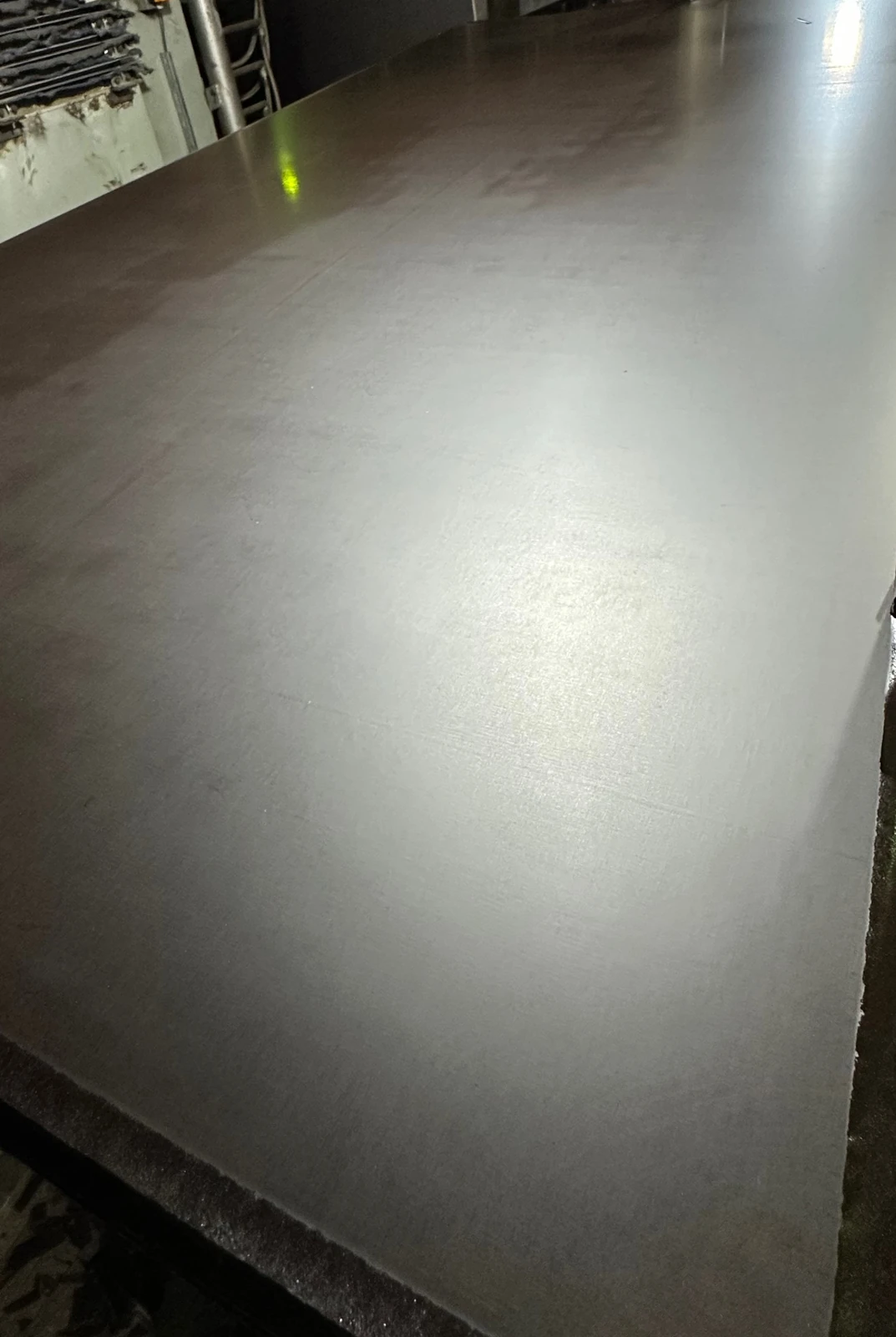 Close view of a smooth dark brown phenolic film face catching soft light